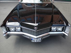 Hood of an American Cadillac with the reflection of a building