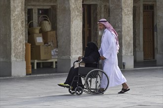 Local man pushing a veiled woman in a wheelchair