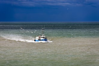 Fishing boat in the sea in front of storm front in Saint-Valery-en-Caux