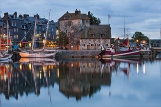 Houses and boats at the old port with reflection in calm waters in the evening