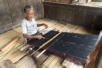Elderly woman weaving ikat cloth