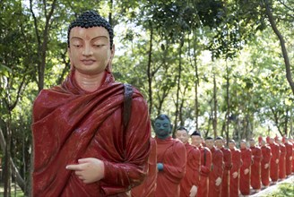 Statues of monks walking behind Buddha