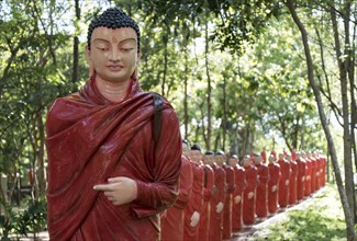 Statues of monks walking behind Buddha