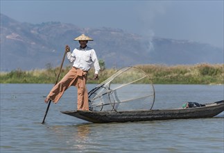 Leg-rowing Intha fisherman with boat on Inle Lake