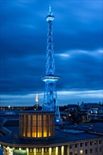 Blue illuminated radio tower at dusk