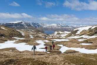 Hikers walking through patches of snow
