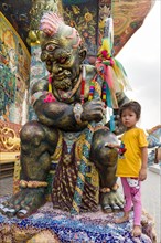 Girl rubbing banknote at a Yaksa statue