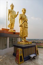 Golden statues of Buddha and monk Luang Phor Khoon on the roof of the Elephant Temple Thep Wittayakhom Vihara