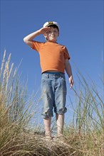 Boy wearing captain's hat on dunes