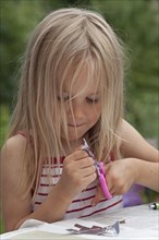 Little girl tinkering with scissors and paper