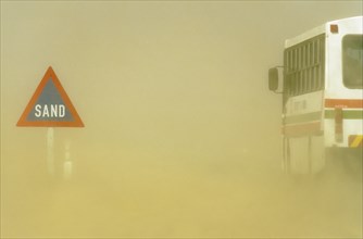 Sand road sign and sandstorm at the B 2 tarred road between Swakopmund and Walvis Bay in the Namib Desert