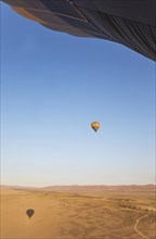 Hot-air balloon above a sandy plain at the edge of the Namib Desert