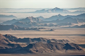 Isolated mountain ridges at edge of Namib Desert with coastal fog behind