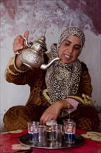 Moroccan woman pouring tea into glasses