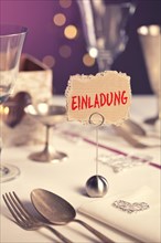 Note on festive table with the inscription Einladung or invitation