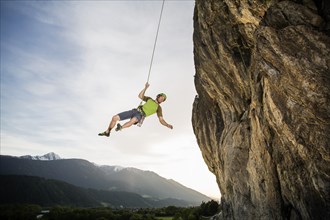 Climber hanging on the rope by the cliff