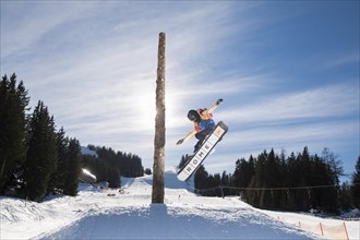 Teenage snowboarder jumping in a funpark