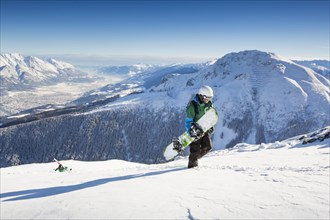 Snowboarders during the ascent overlooking Innsbruck and Inntal valley