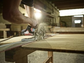 Carpenter cutting chipboard with a circular saw
