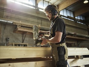 Carpenter nailing chipboard to a wooden beam