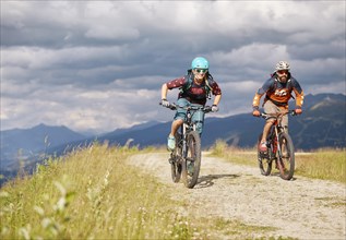 Two mountain bikers with helmets riding on gravel roads