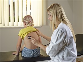 Pediatrician examining young blonde girl with stethoscope