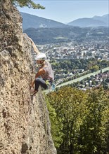 Female climber with helmet climbing on a rockface
