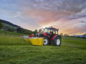 Tractor mowing a field at sunrise
