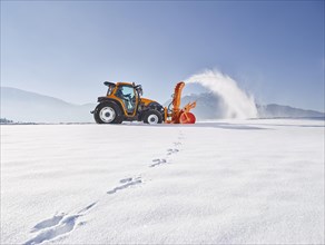 Tractor with a snow blower clearing snow