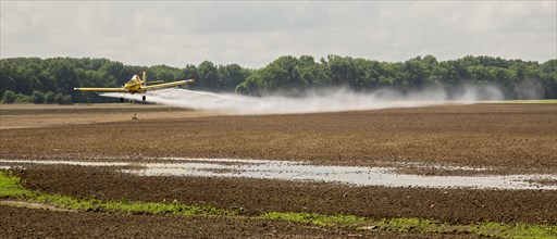 Crop duster airplane applies pesticides to a field in the Mississippi Delta