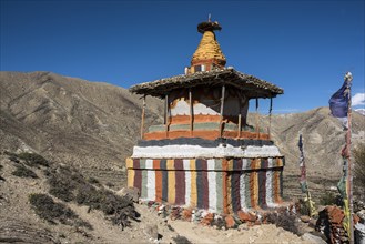 Colourfully painted Buddhist stupa in front of mountain landscape