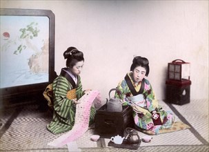 Two geishas reading and drinking tea