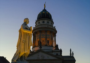 Schiller sculpture on Gendarmenmarkt square in front of the dome of the French Cathedral in the evening