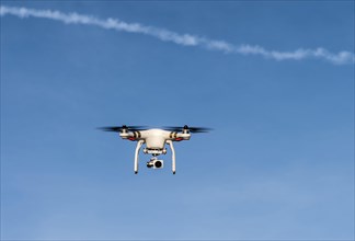 Quadcopter with camera flying in front of a blue sky