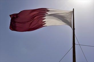 Qatar flag against a blue sky waving in the wind