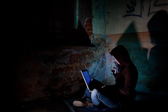 Female computer hacker sitting with a laptop in the dark