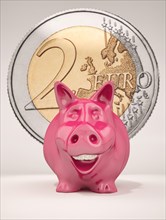 Smiling piggy bank with a 2 euro coin