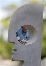 Sculptor works with hammer and chisel on head