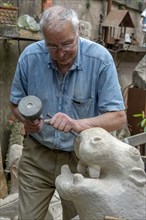 Sculptor working with hammer and chisel on hippopotamus figure