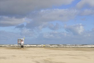 Beach at the stormy North Sea with rescue tower