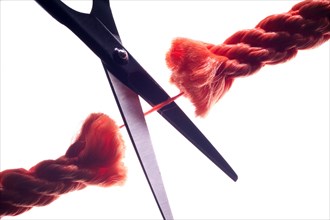 Scissors cutting the last remaining thread of a rope