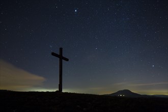 Summit cross on Bisberg Mountain with a starry sky