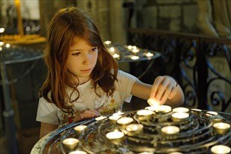 Girl lighting a devotional candle at Notre-Dame de Paris or Notre-Dame Cathedral