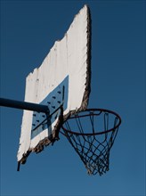 Weathered basketball hoop against a blue sky