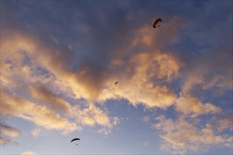 Paraglider in front of clouds at dusk