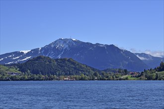 Snow-covered Grunten Mountain behind Alpsee lake