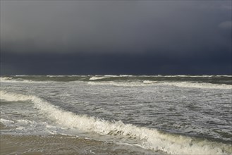 Waves on a sandy beach in front of a rain front over the North Sea