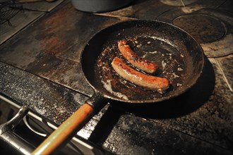 Two Franconian sausages in an old cast iron skillet on an old stove