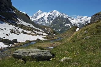 Valley with the Louvie stream in an alpine landscape with the peaks of Combin de Corbassiere Mountain