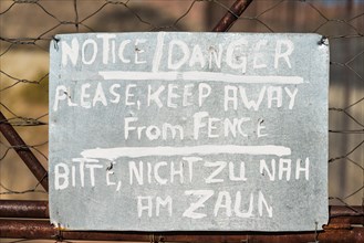 Warning sign in English and German on the fence of a predator enclosure